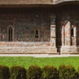 Fațada pictată a unei mănăstiri din Bucovina, cu fresce exterioare în nuanțe de albastru și verde