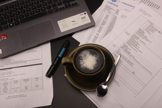 Calculator, carnet cu notițe și laptop pe un birou, folosite pentru calculul prețului unui serviciu