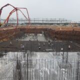 Perete de fundație acoperit cu membrană hidroizolantă neagră, pe un șantier de construcții